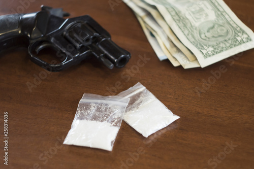 revolver drugs money on wood table
