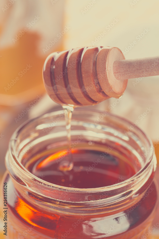 Honey background. Sweet honey in glass jar on wooden background. Honey background. Sweet honey in glass jar on wooden background.