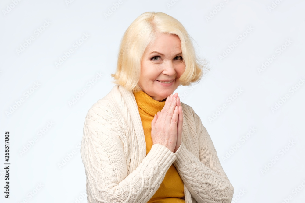 blonde woman with tender smile, keeps both palms on chest blonde woman with tender smile, keeps both palms on chest
