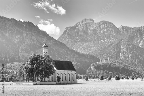 Bavarian landscape in black-and-white color  - view of the church of St. Coloman on the background of the Alpine mountains and Neuschwanstein Castle, Germany photo