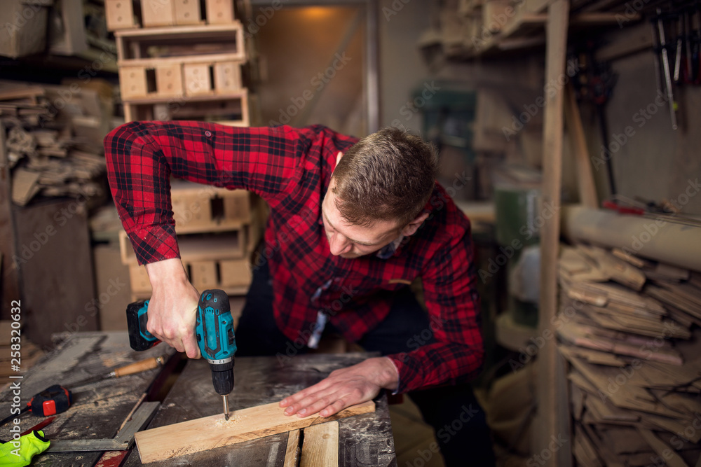 Male carpenter in his workshop using drill Male carpenter in his workshop using drill