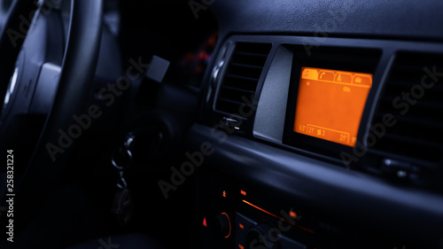 Buttons of radio, dashboard, climate control in car close up - black and orange