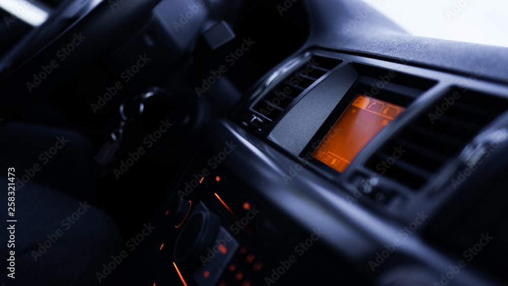 Buttons of radio, dashboard, climate control in car close up - black and orange
