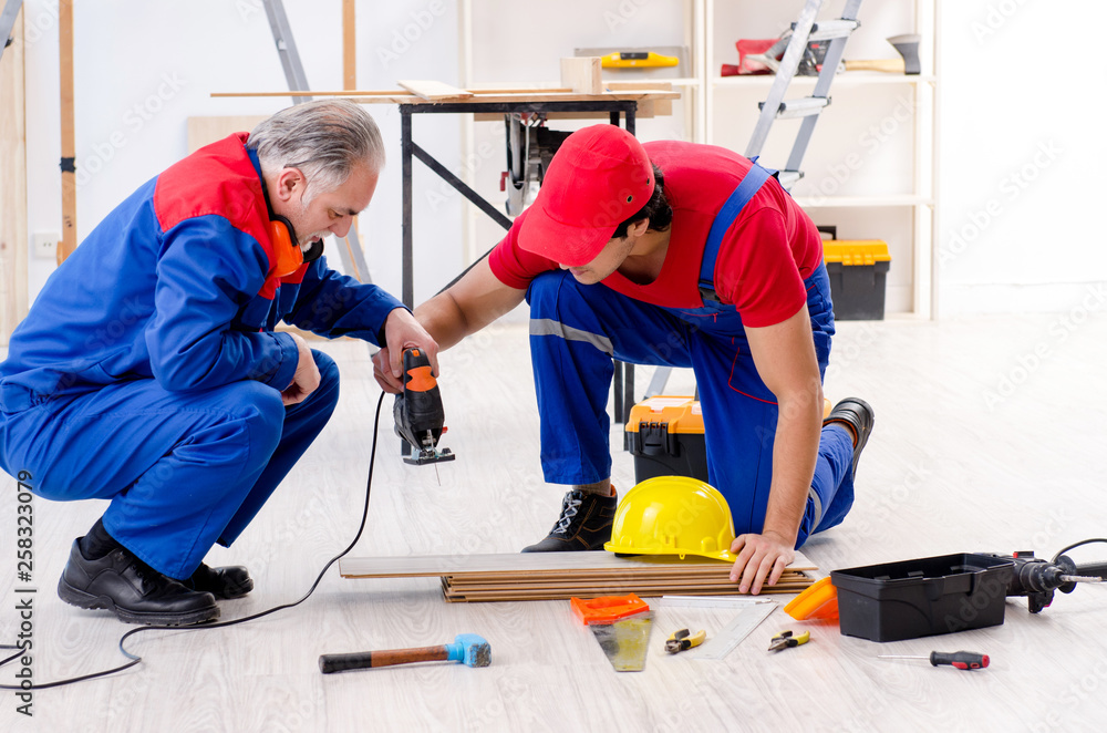 Two professional contractors laying flooring at home Two professional contractors laying flooring at home