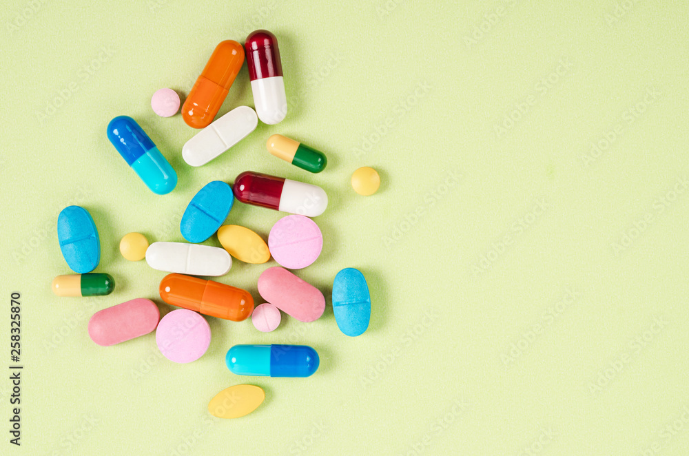 Heap of various pills on color background.