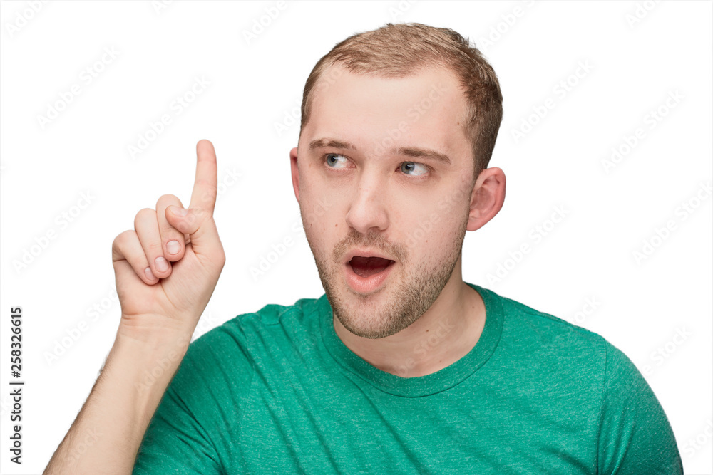 A funny young man in a green shirt shows one A funny young man in a green shirt shows one