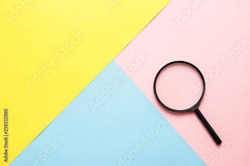 Magnifier on colored paper. Top view. Search concept