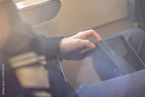 Caucasian boy fasten seat belt and using tablet pc during air flight.  Safety travel with kid. concept photo