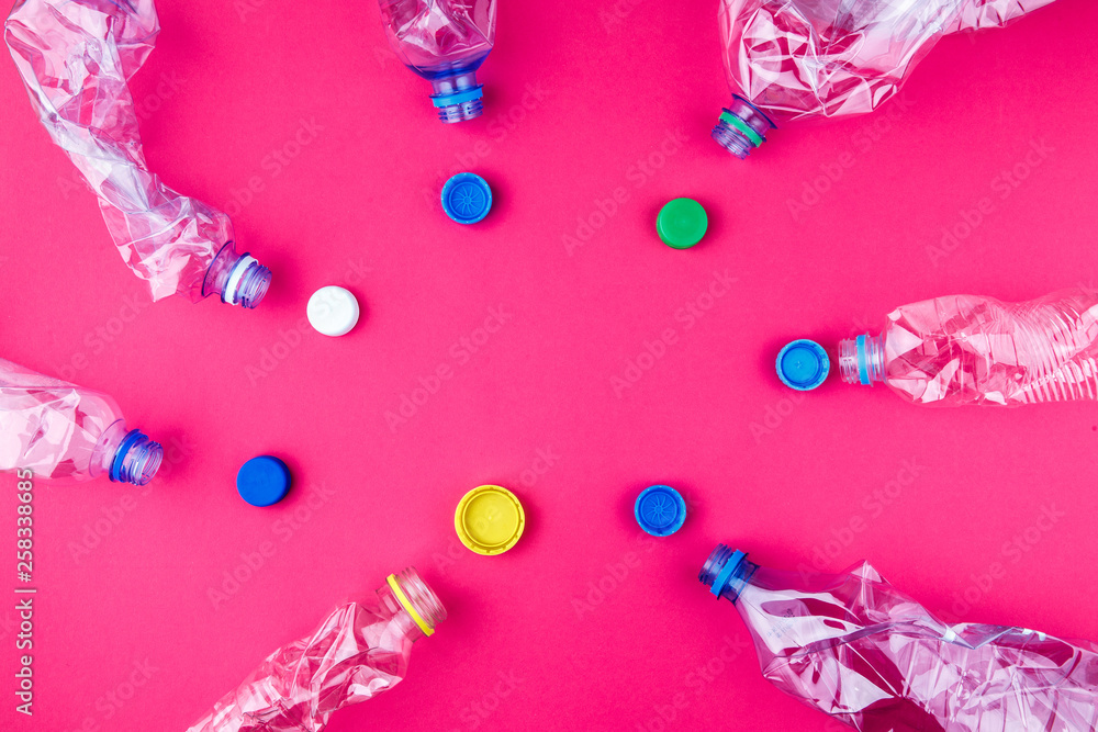 Crushed plastic bottles and colorful caps on vivid pink purple background. Crushed plastic bottles and colorful caps on vivid pink purple background.