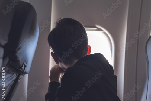 A boy have flight looking in the airplane window or porthole. photo