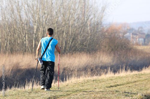 Scandinavian nordic walking. A man in sports clothes stroll through the spring s grass in the rays of sunlight. Healthy lifestyle. Sports event. A example of society