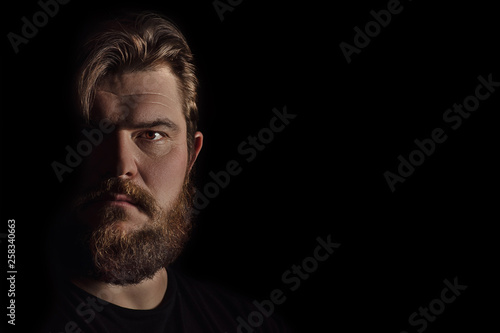 Close-up portrait strong serious brutal bearded man on black. Confident and dramatic concept