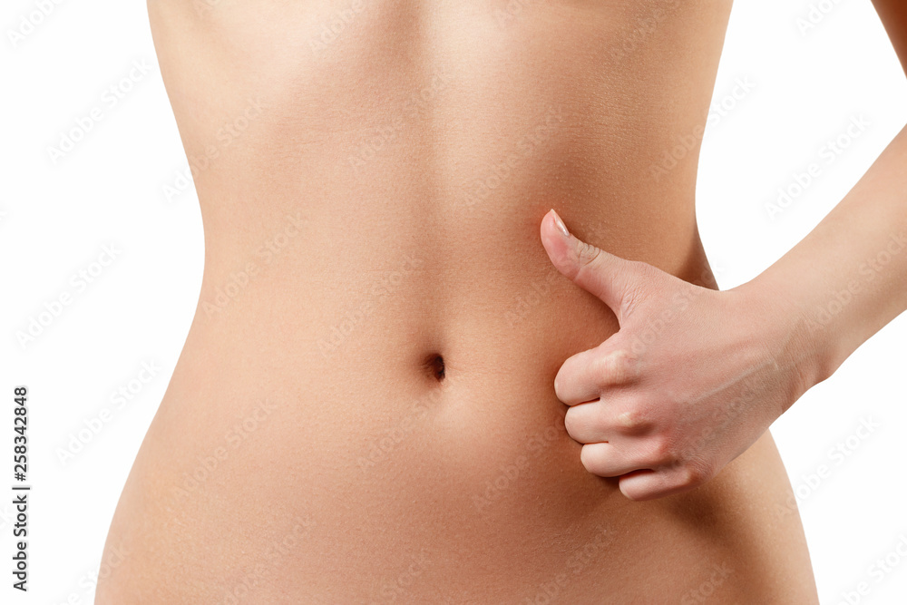 slim, athletic waist of a young woman on white background. The hand in the foreground shows a finger up gesture. the concept of female beauty and health, nutrition and diet, beautiful figure slim, athletic waist of a young woman on white background. The hand in the foreground shows a finger up gesture. the concept of female beauty and health, nutrition and diet, beautiful figure