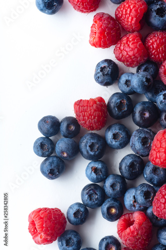 Raspberries and blueberries isolated on white background with copy space