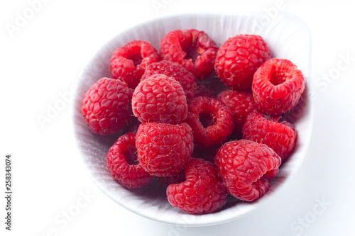 Fresh raspberries in ceramic bowl isolated on white background