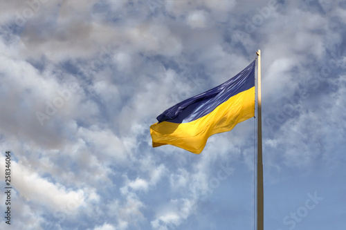 Blue and yellow Ukrainian national flag on a flagpole against a blue cloudy sky, copy space for text. presidential elections in Ukraine 2019.