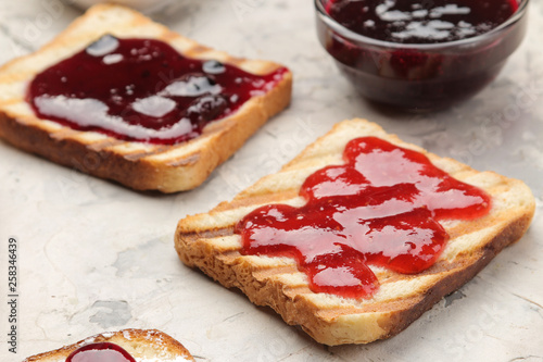 toasts with jam. fried crispy toasts with red jam on a light concrete table. breakfast. close-up
