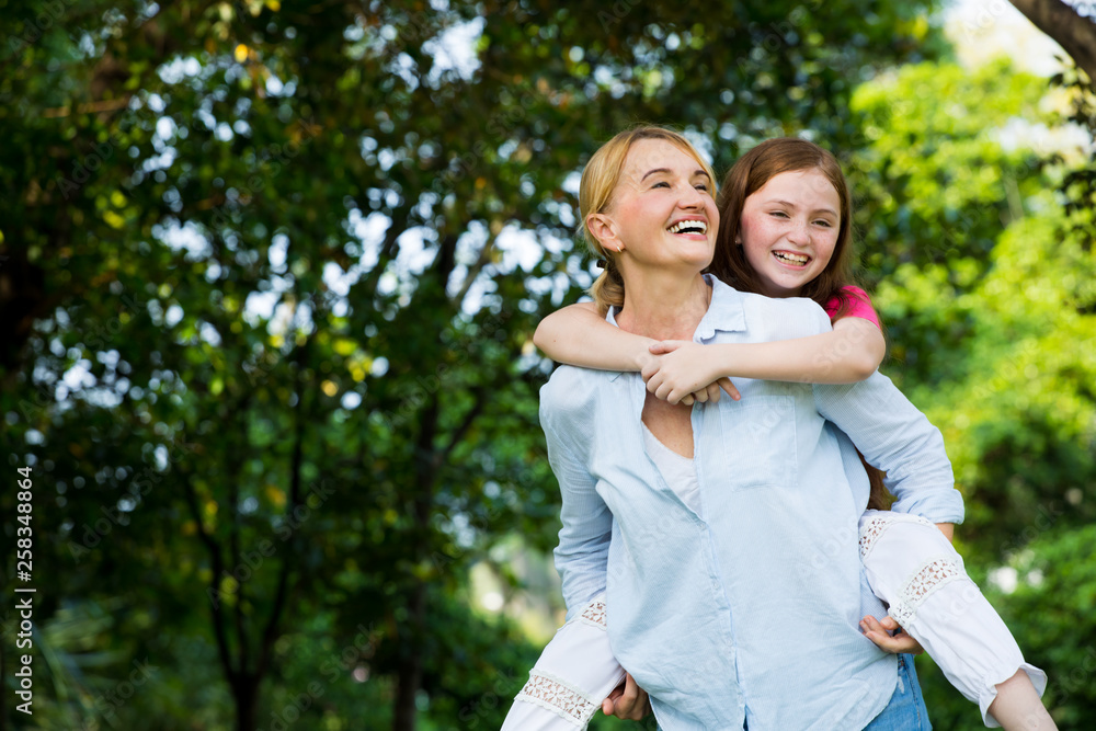 Small happy girl enjoying a piggyback ride on her mothers back Small happy girl enjoying a piggyback ride on her mothers back