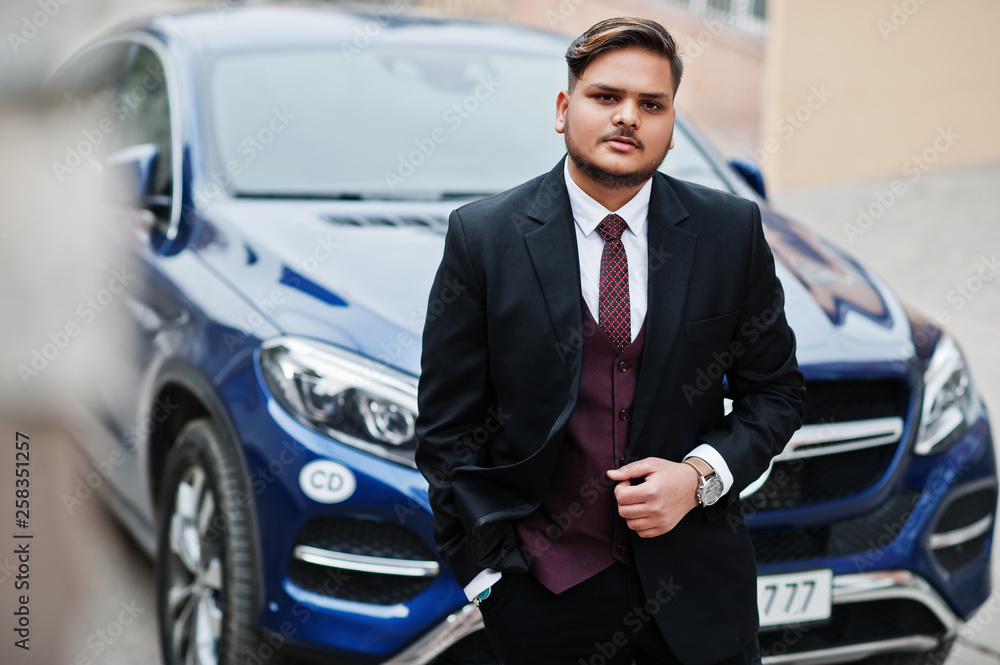 Rich indian businessman in formal wear standing against business suv car.
