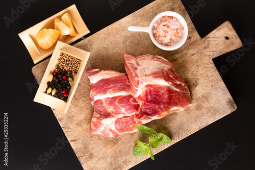 Food concept piece boneless Pork collar on cutting board with spice on black background with copy space