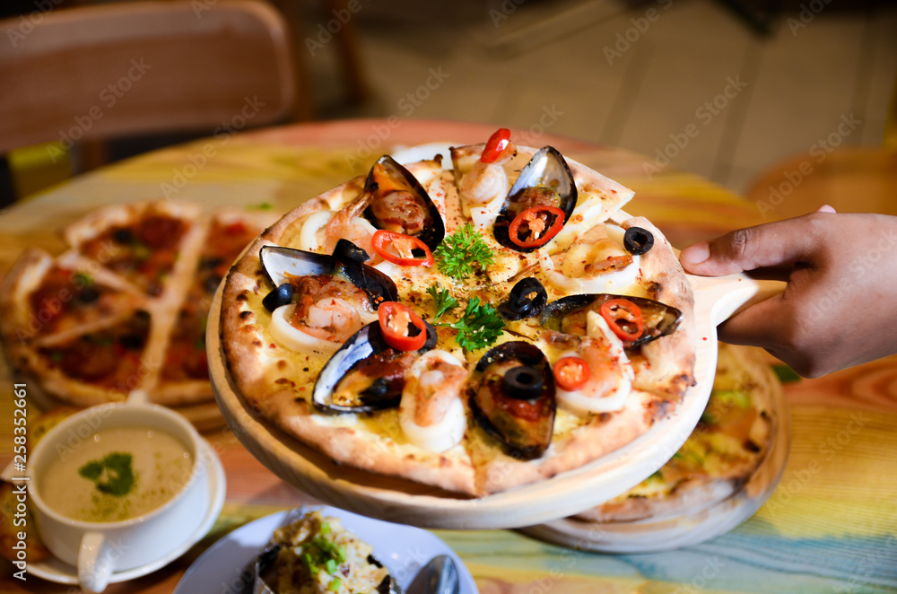 Slice of hot pizza cheese lunch or dinner crust seafood meat topping sauce with bell pepper vegetables delicious tasty fast food italian traditional on wooden board table classic with delivery hand 
