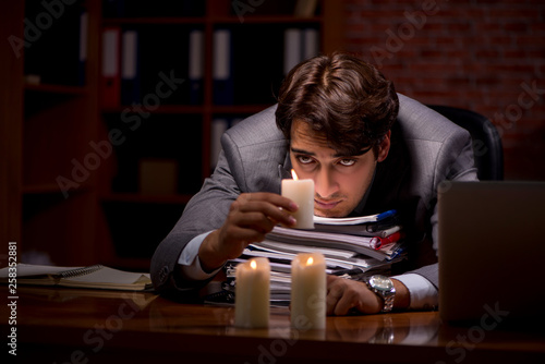 Businessman working late in office with candle light photo
