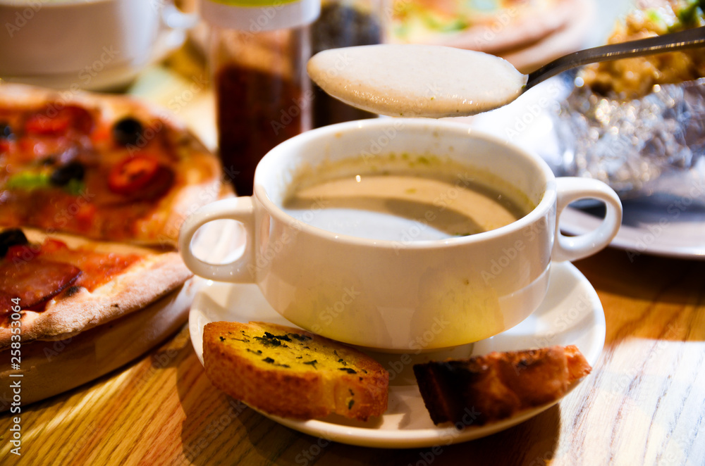 Bowl on a table with mushroom soup and a spoon hovering above Bowl on a table with mushroom soup and a spoon hovering above