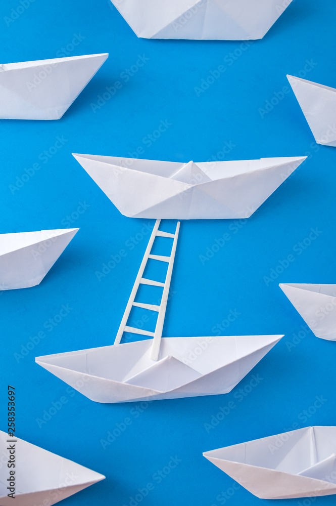 White paper boats with a ladder on a blue background White paper boats with a ladder on a blue background