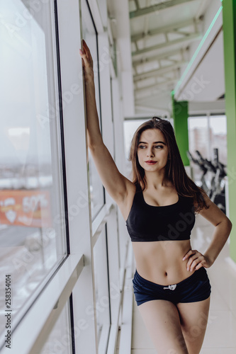 Workout, fitness and sport concept. Pretty sporty woman standing near window in gym