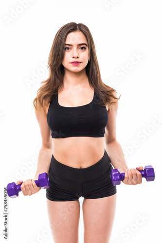 Sporty woman does the exercises with dumbbells on white background. Portrait of muscular woman in sportswear on white background. Strength and motivation.