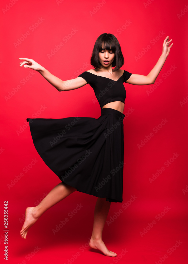 Naklejka premium Beautiful woman in black flying dress isolated on red background