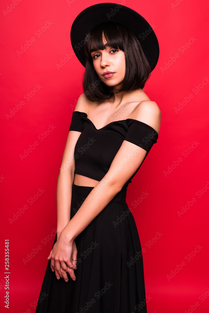 Young brunette woman in fluppy hat and black clothes on red background Young brunette woman in fluppy hat and black clothes on red background