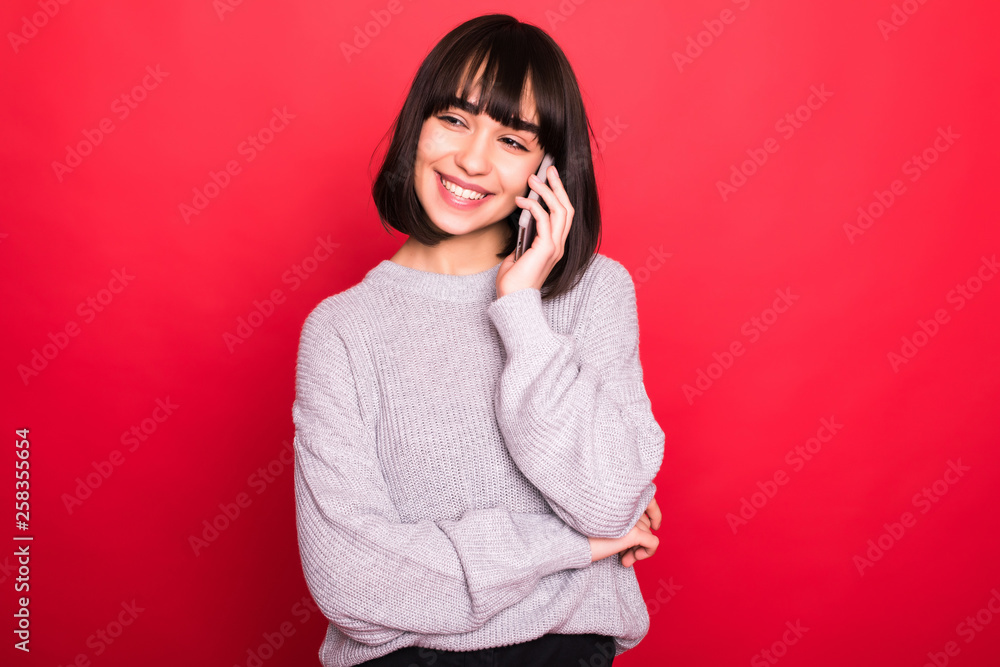Pretty young woman calling by phone against red background Pretty young woman calling by phone against red background