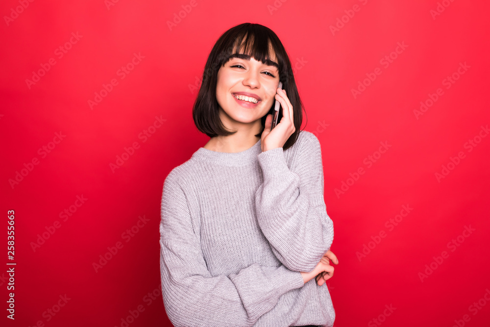 Young pretty woman talking on the phone isolated on red background Young pretty woman talking on the phone isolated on red background