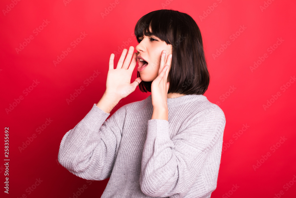 Woman shouting and announcing something isolated on red background Woman shouting and announcing something isolated on red background