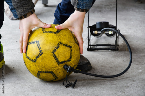 The boy is pumping the ball for the game of football, foot pump.