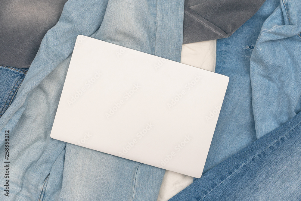 Laptop lying on the many different jeans scattered on the floor. Concept. Laptop lying on the many different jeans scattered on the floor. Concept.