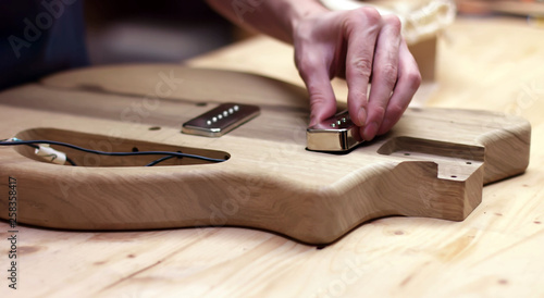 Obraz na plátně Luthier assembles electrical parts into handmade guitar