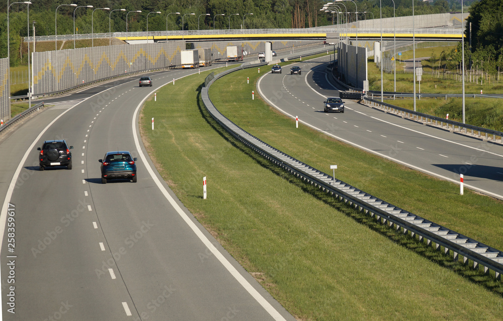 Car traffic on a fast-moving road built with sound absorbing panels. Noise protection.