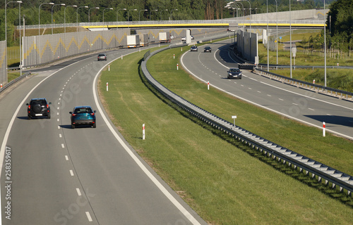 Car traffic on a fast-moving road built with sound absorbing panels. Noise protection. © Wlodzimierz