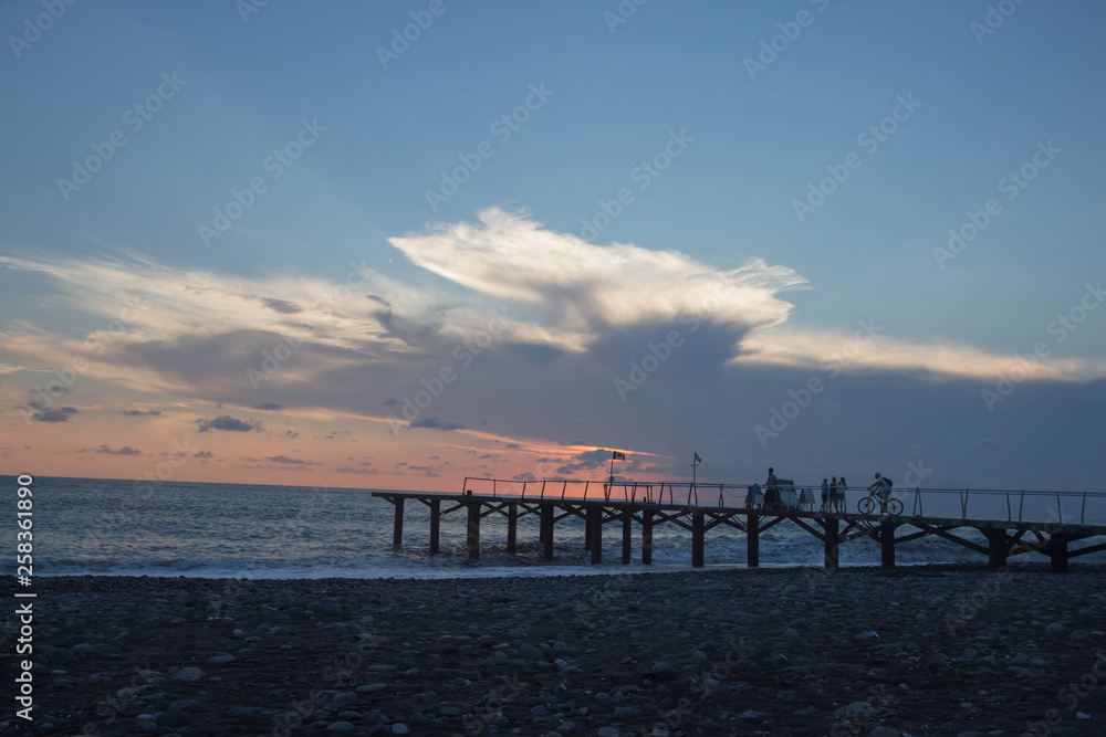sun setting over Batumi beach Jetty, as powerful waves roll in, and a very colorful sky is reflected on the beach