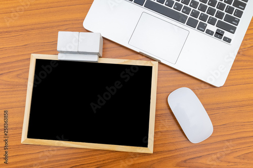 Top view. Small blackboard rectangular wooden blocks mouse computer and laptop put on wood background with texture. Free space on the blackboard for text input.