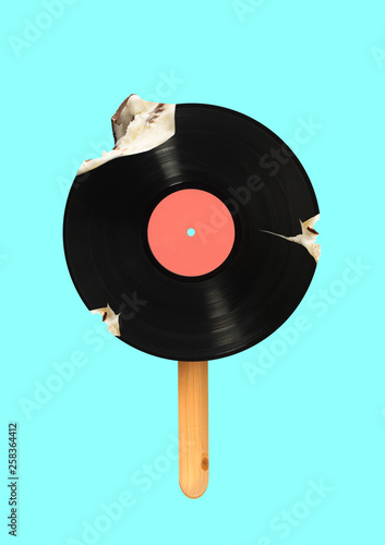 An alternative icecream. Meloman wanna bite a piece of immortal music. Vinyl record formed icecream on a wooden stick against blue sky colored background. Modern design. Contemporary art collage.