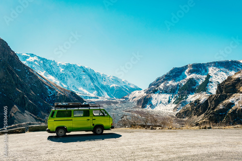 Vintage classic van parked beside the road among the high Caucasus peaks on the far north of Georgia. Breath taking view. © predragmilos