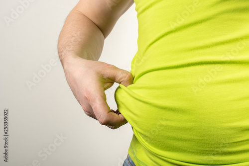 A man in jeans and a t-shirt with a fat belly on a white background.