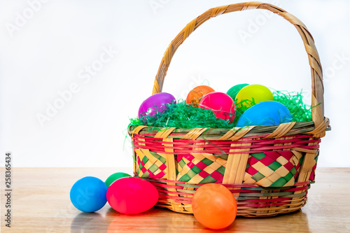 Easter basket with colorful plastic Easter eggs. Vintage woven wicker egg hunt basket, green grass, and vibrant colored classic eggs.