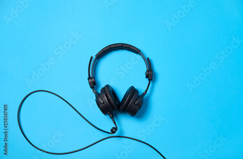 Music or podcast background with headphones on blue table, flat lay. Top view, flat lay, space for text