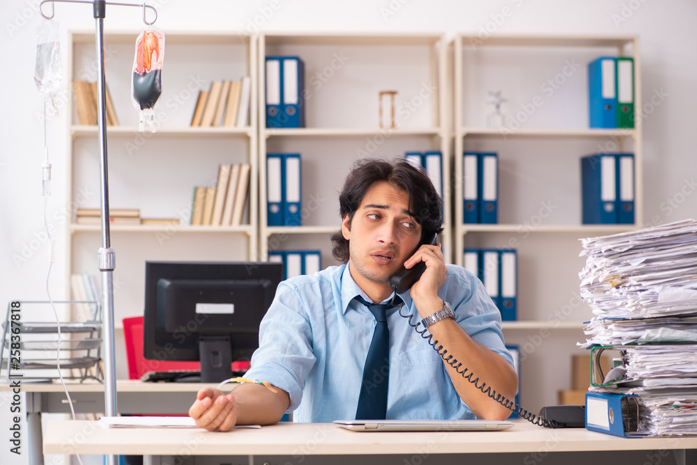 Young male employee in blood transfusion concept Young male employee in blood transfusion concept