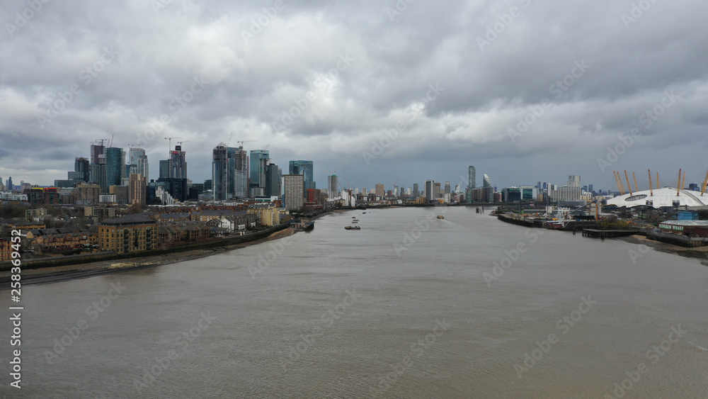 Aerial bird's eye view photo taken by drone of Canary Wharf skyline as seen from river Thames with beautiful cloudy sky, Isle of Dogs, London, United Kingdom