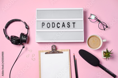 Music or podcast background with headphones, microphone, coffee and blank on pink table, flat lay. Top view, flat lay © Boyarkina Marina